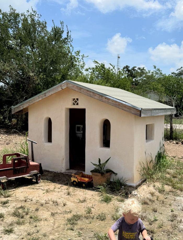 Cob playhouse with arched windows and standing seam roof