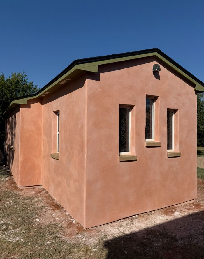 Terracotta lime plaster gable end with stained glass windows