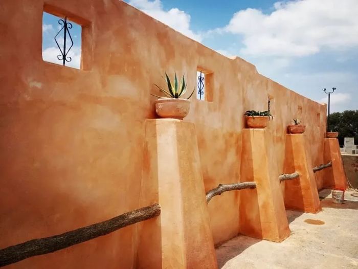 Terracotta courtyard wall with potted plants and pier caps