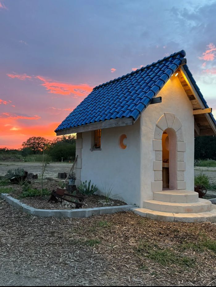 Cob building with tile roof at sunset