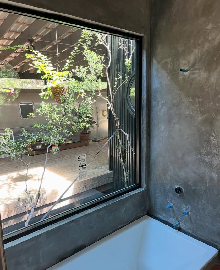 Tadelakt tub surround with courtyard window view, plumbing rough-in