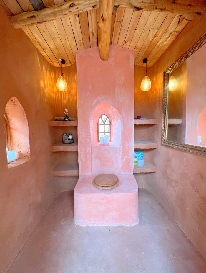 Pink clay plaster interior with built-in shelving and arched window