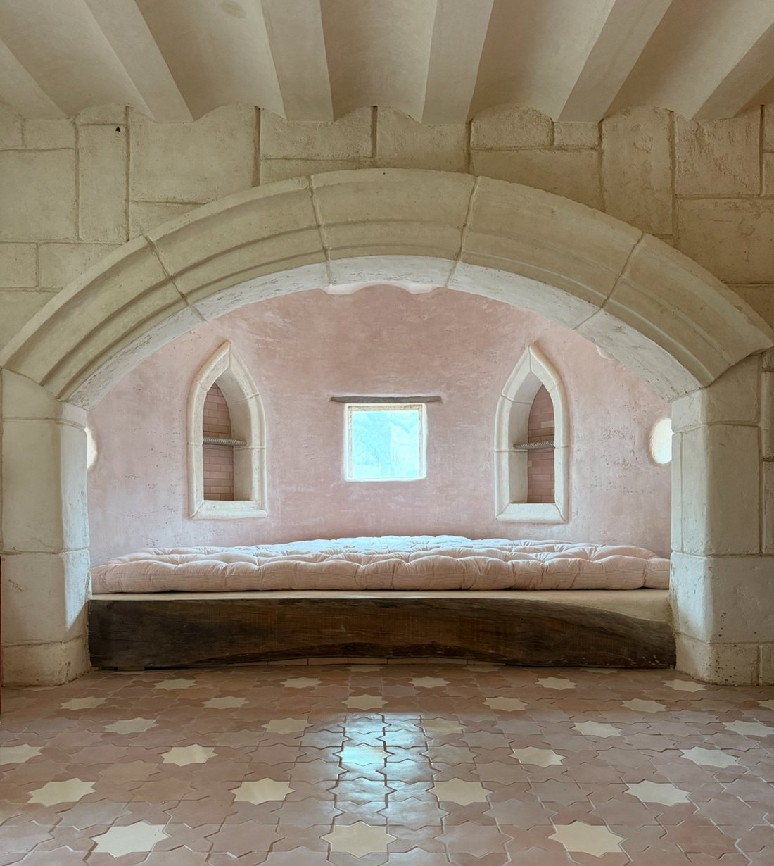 Pink lime plaster alcove with carved stone arch, arched niches and star tile floor
