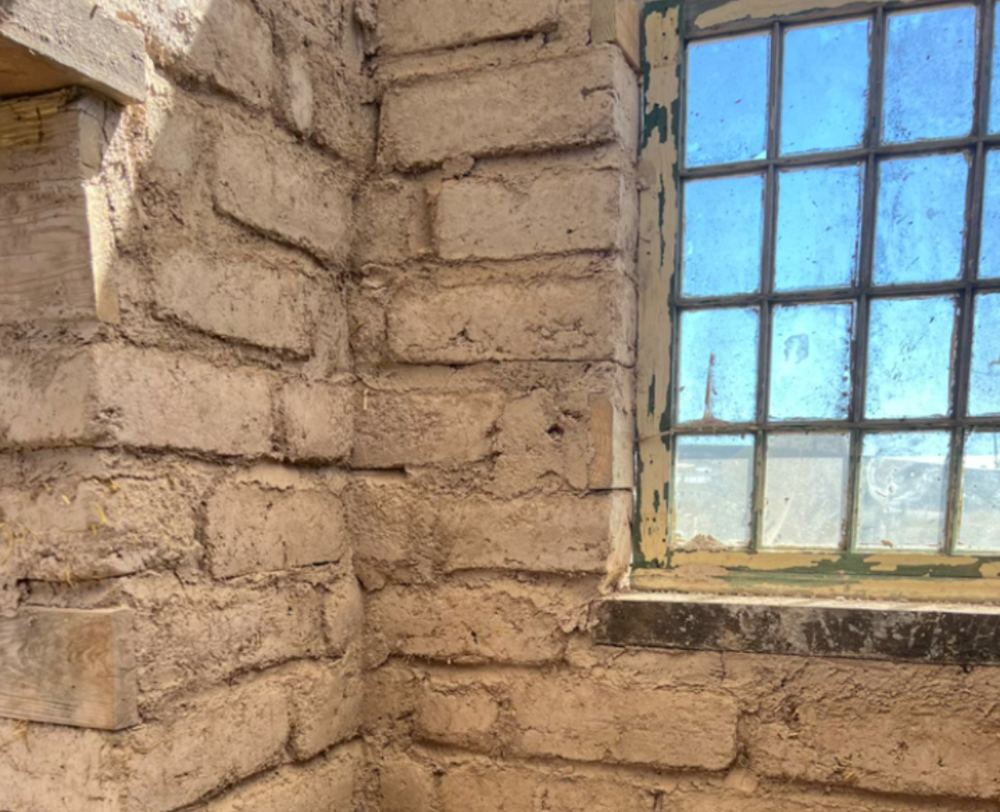 Adobe brick wall meeting a salvaged window frame